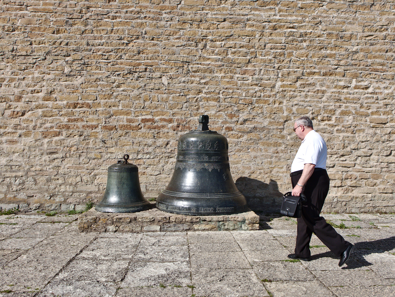 Man walking by two church bells. Narva, Estonia.