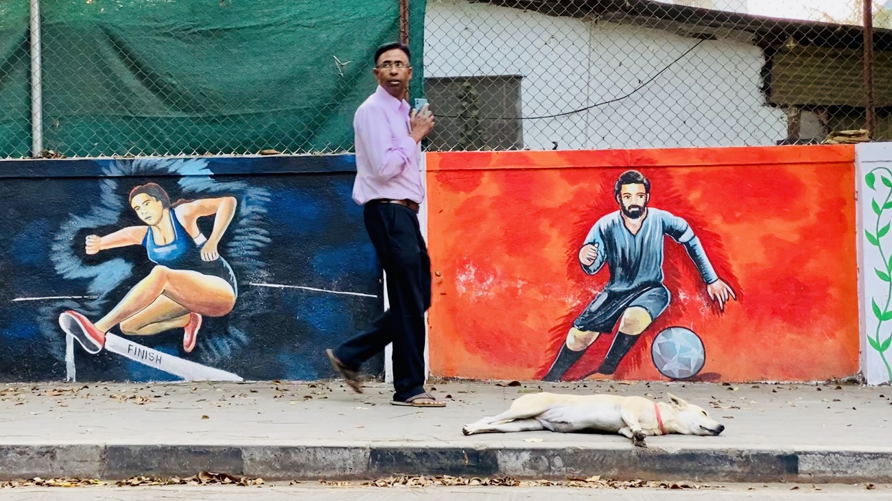 Man walking by graffitis in Koregaon Park, Pune, India.